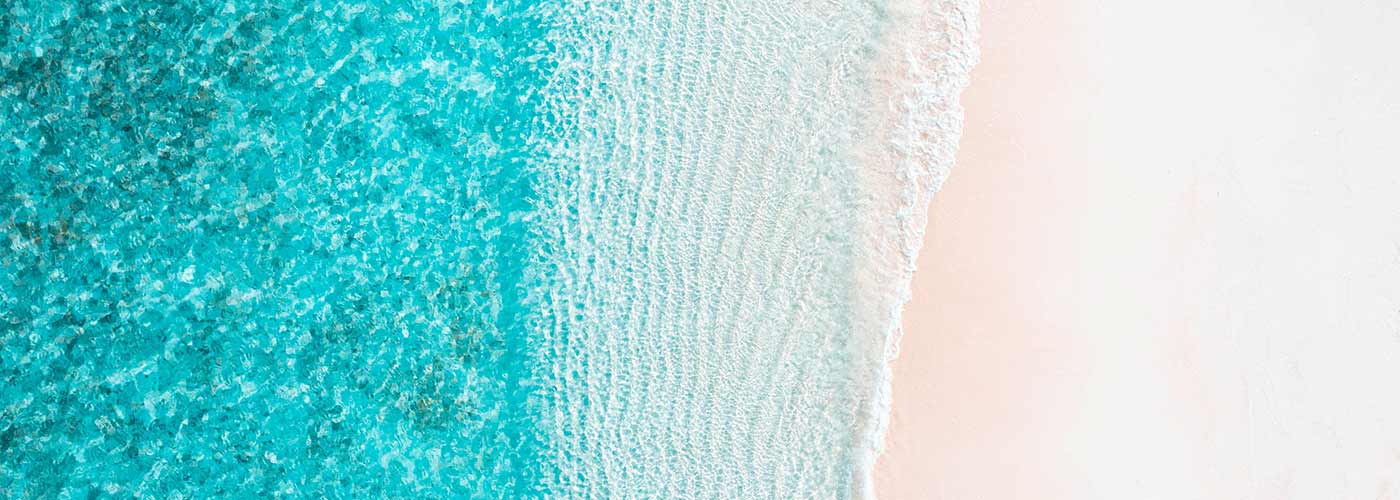 Aerial view of a beautiful beach, with clear blue sea lapping up on white sand.