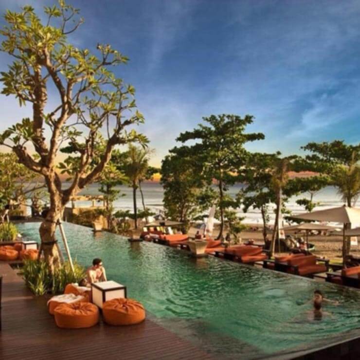 A stunning pool at a bali hotel resort, lines with native trees.