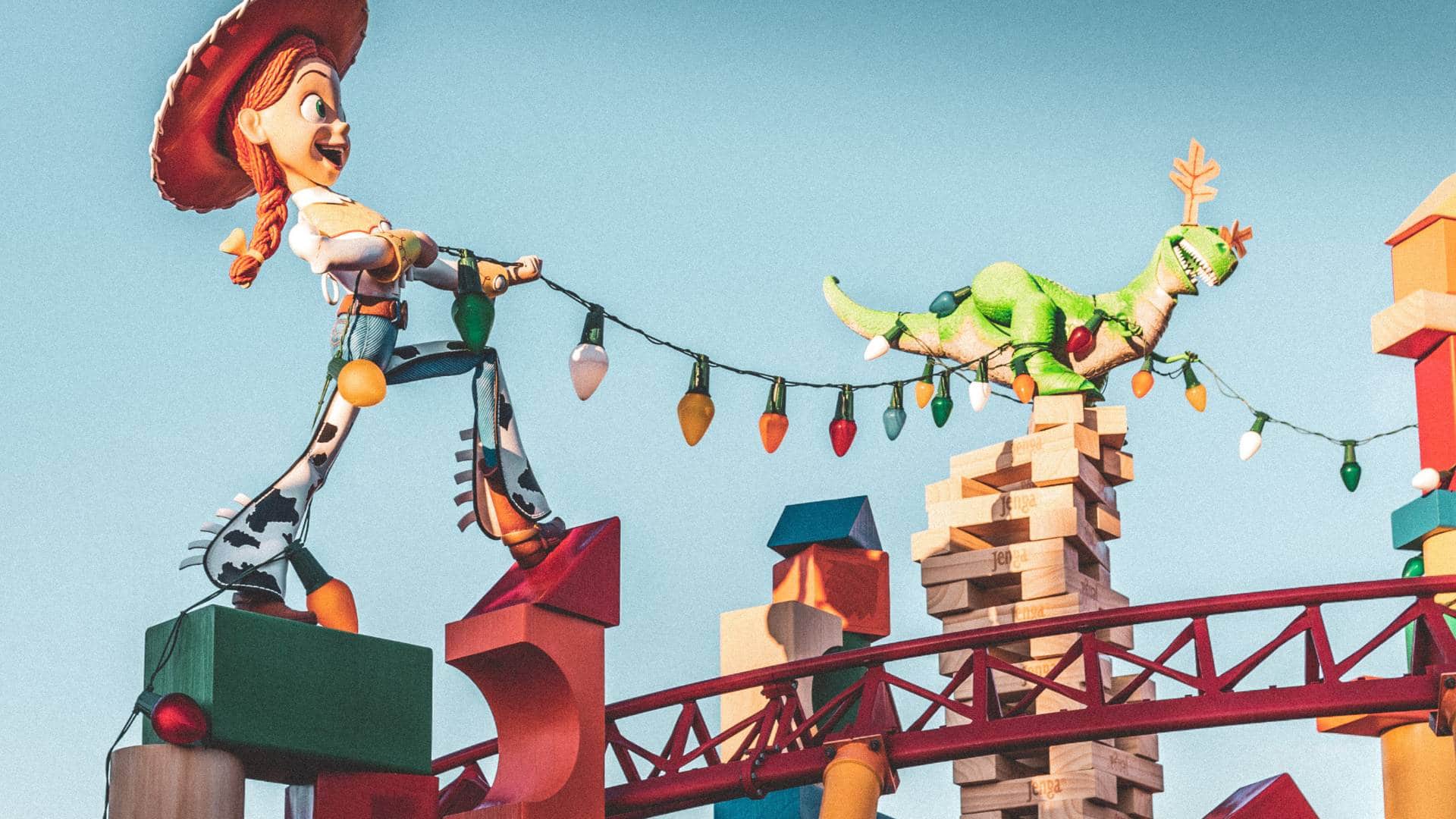 Jessie the cowgirl and Rex the dinosaur from Toy Story arranging Christmas lights on a playful, colorful structure.