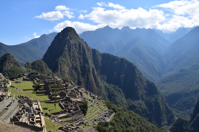 Panoramic view of Machu Picchu ruins with Huayna Picchu mountain in the background under blue sky with clouds