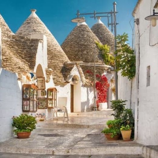 Traditional cone-roofed trulli houses along a whitewashed lane in Alberobello, Puglia